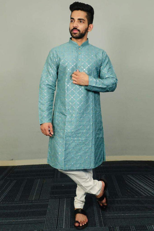 Man posing in a light blue embroidered kurta with white churidar pants, festive ethnic wear