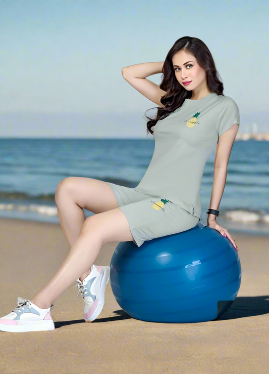 Woman in light green pineapple print lounge set on beach stability ball, casual summer fashion