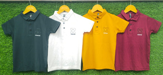 Four kids' polo shirts in black, white, yellow, and maroon with adventure print, displayed on hangers