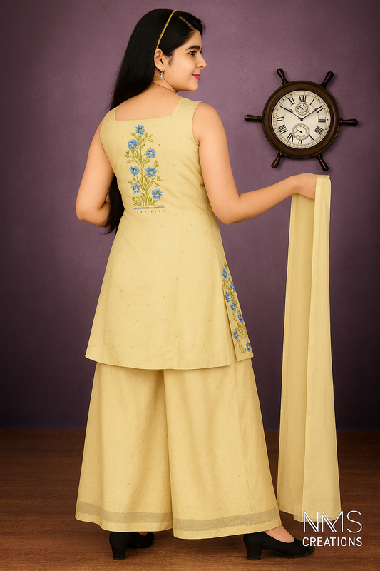 Woman in a light green traditional outfit with floral embroidery, holding a dupatta, against a purple wall with a clock.