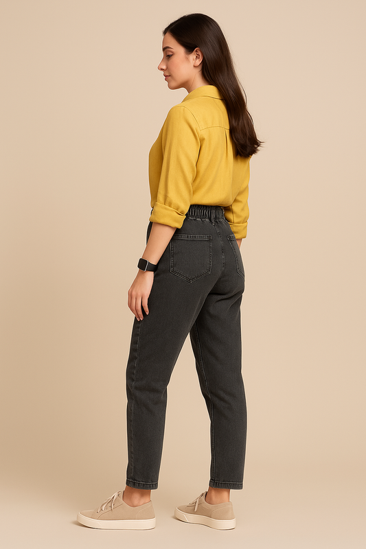 Woman wearing a yellow shirt and dark jeans on a beige background