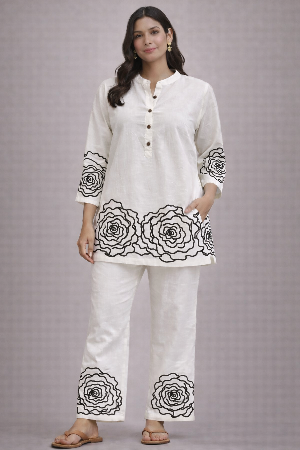 Woman wearing a white kurta with black floral embroidery on a gray background