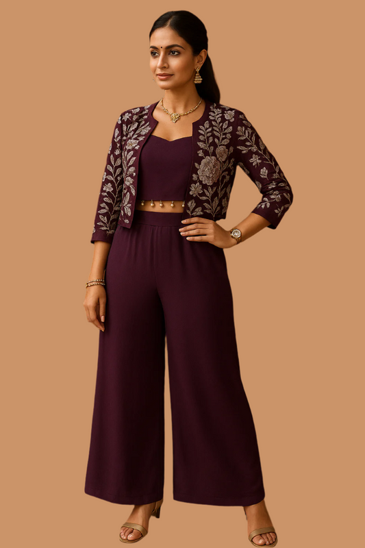 A woman modeling a Royal Wine three-piece Indo-Western palazzo set with a crop top, palazzo pants, and a waist-length jacket, all embroidered with silver and blush floral motifs.