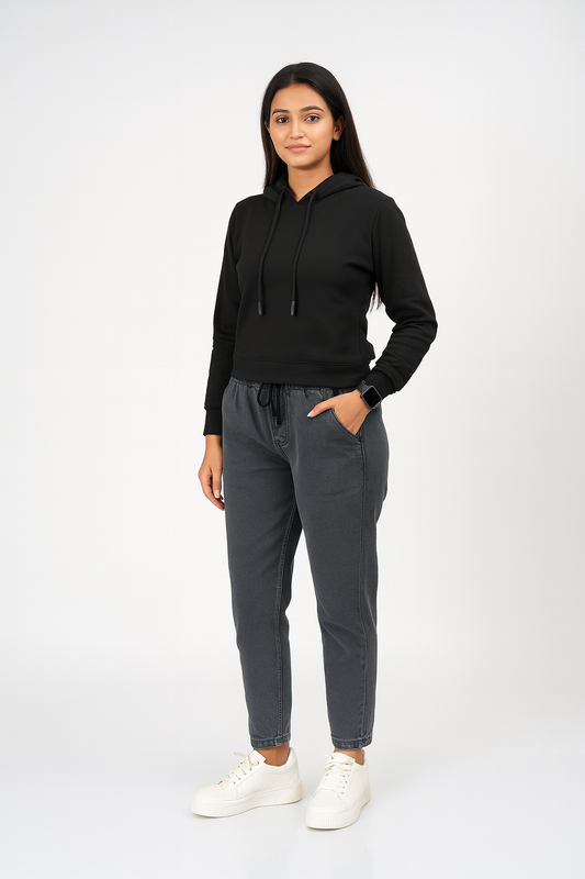 Woman wearing a black hoodie and gray sweatpants on a white background