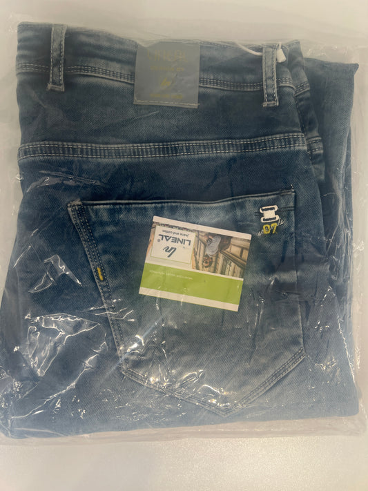 Folded blue denim jeans in plastic packaging on a white surface