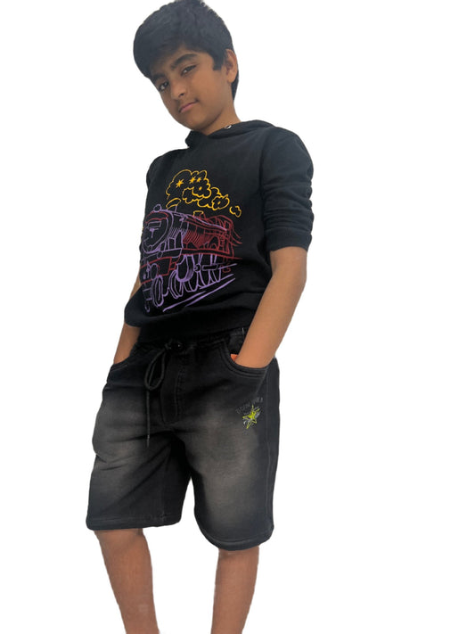 Boy in black graphic hoodie and faded black shorts posing on white background