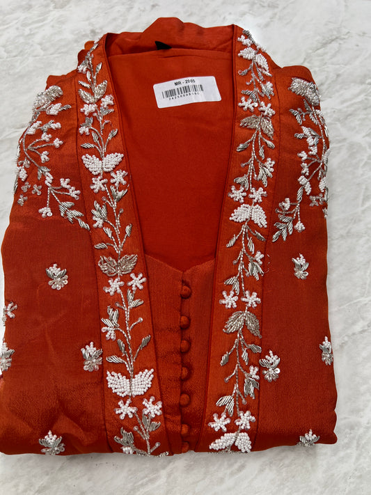 Red embroidered festive kurta with floral silver and white threadwork, folded on marble