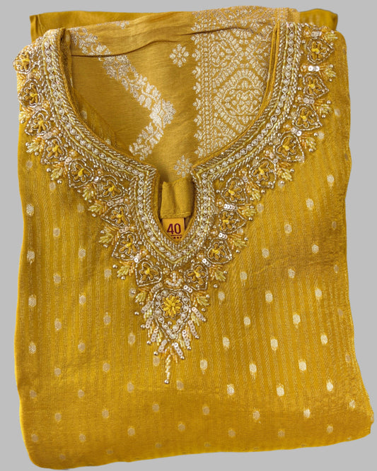 Folded yellow festive kurta with intricate sequin embroidery and white pattern accents