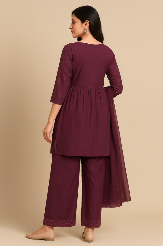 Woman wearing a maroon outfit with a matching top and wide-leg pants on a beige background