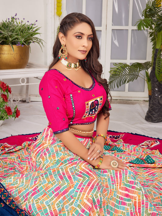 Woman in vibrant traditional lehenga choli with jewelry, seated indoors, festive setting