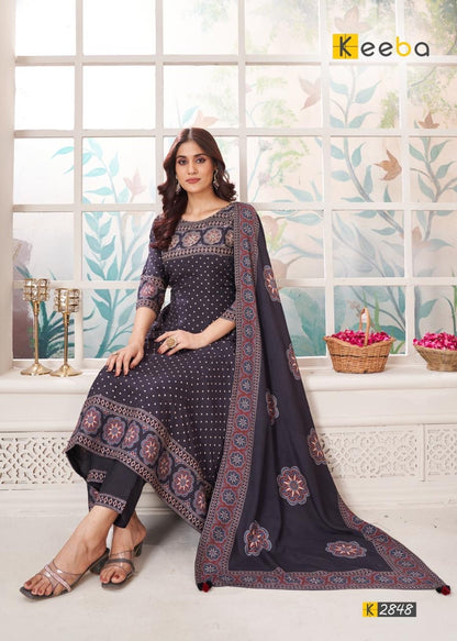 Woman in dark blue printed ethnic suit with dupatta, sitting in bright indoor setting