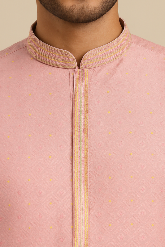 Close-up of a pink traditional outfit with a collar and yellow patterns on a beige background