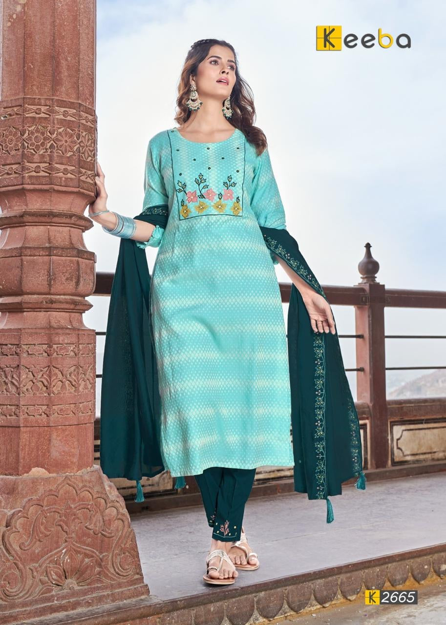 Woman in a stylish turquoise and navy blue ethnic suit with floral embroidery, standing outdoors