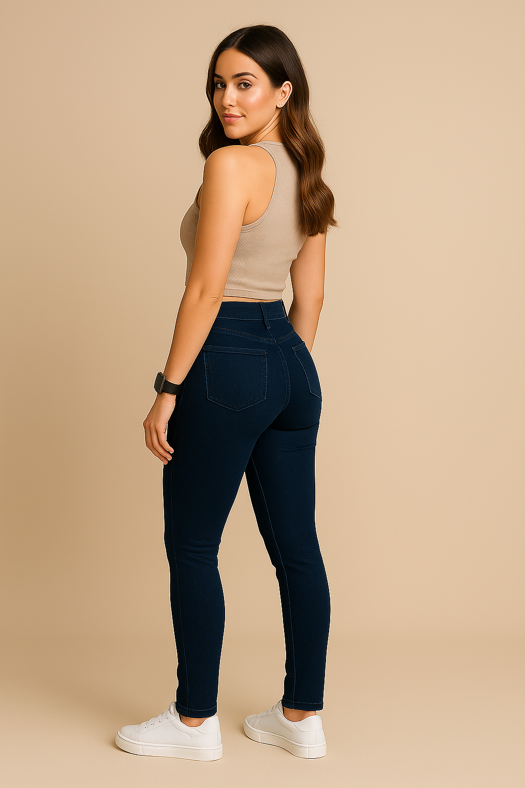 Woman wearing navy blue jeans and a beige top on a beige background