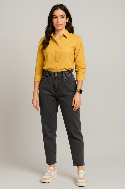 Woman wearing a yellow shirt and black jeans on a plain background