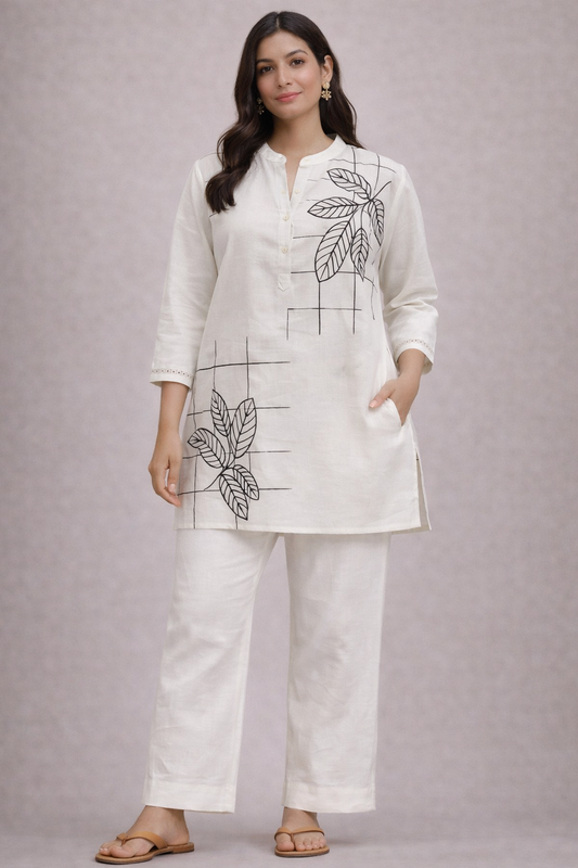 Woman wearing a white outfit with leaf patterns on a plain background