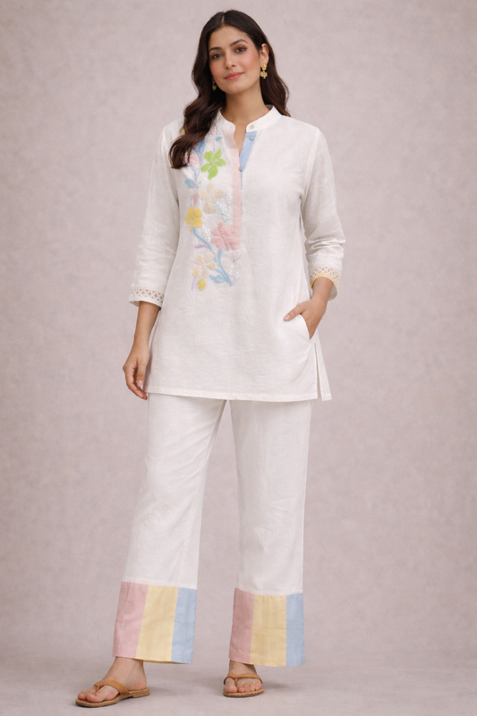 Woman wearing a white outfit with colorful accents on a light gray background