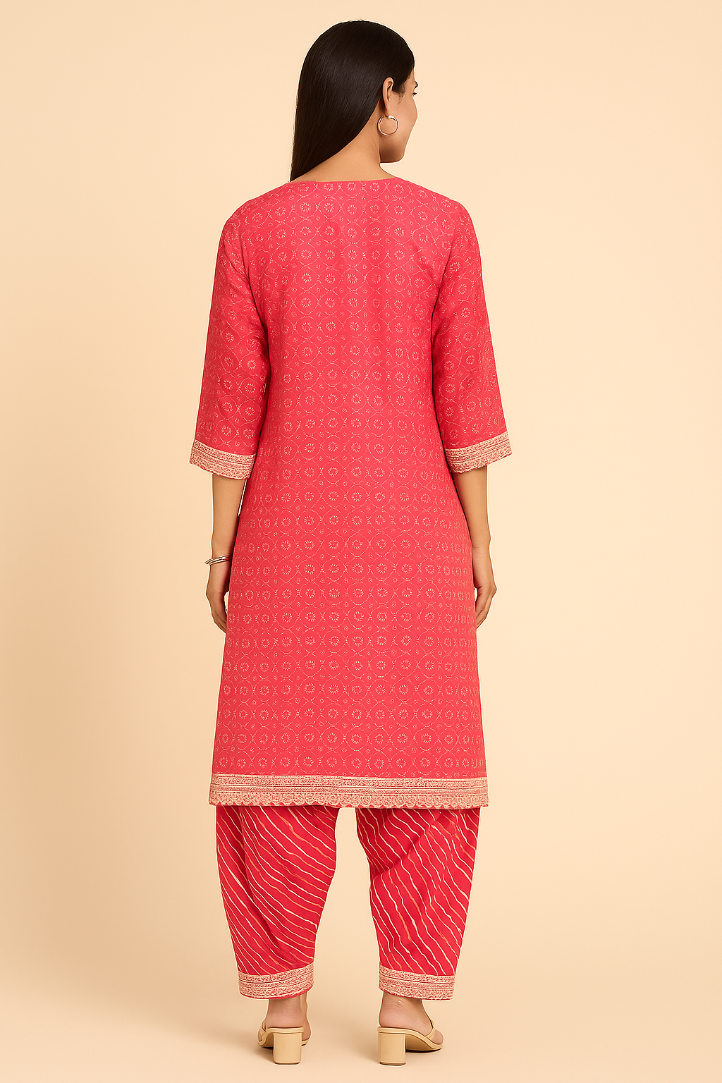 Woman wearing a pink kurta with matching pants on a beige background