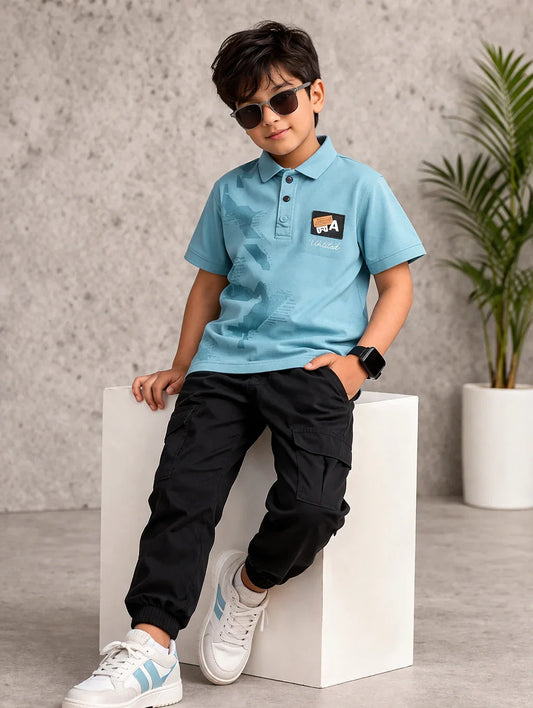 Stylish boy in blue polo shirt, black jogger pants, and white sneakers, wearing sunglasses.