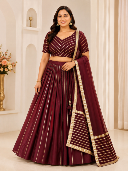 Woman wearing a maroon traditional outfit with gold accents in a well-lit room.