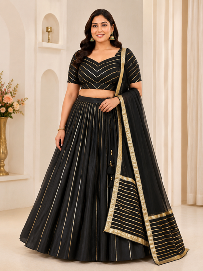Woman wearing a black and gold traditional outfit with a dupatta in an elegant indoor setting.