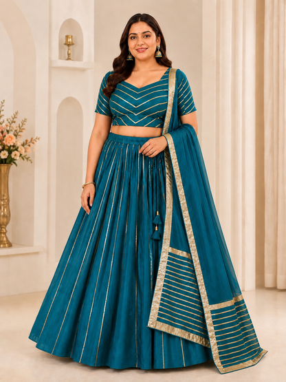 Woman wearing a teal traditional outfit with gold details in a decorated room.
