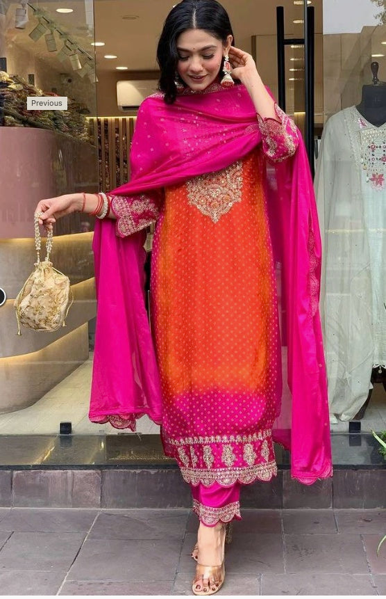 Woman in orange and pink embroidered festive salwar suit with dupatta and gold bag