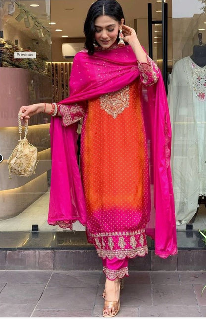 Woman in orange and pink embroidered festive salwar suit with dupatta and gold bag