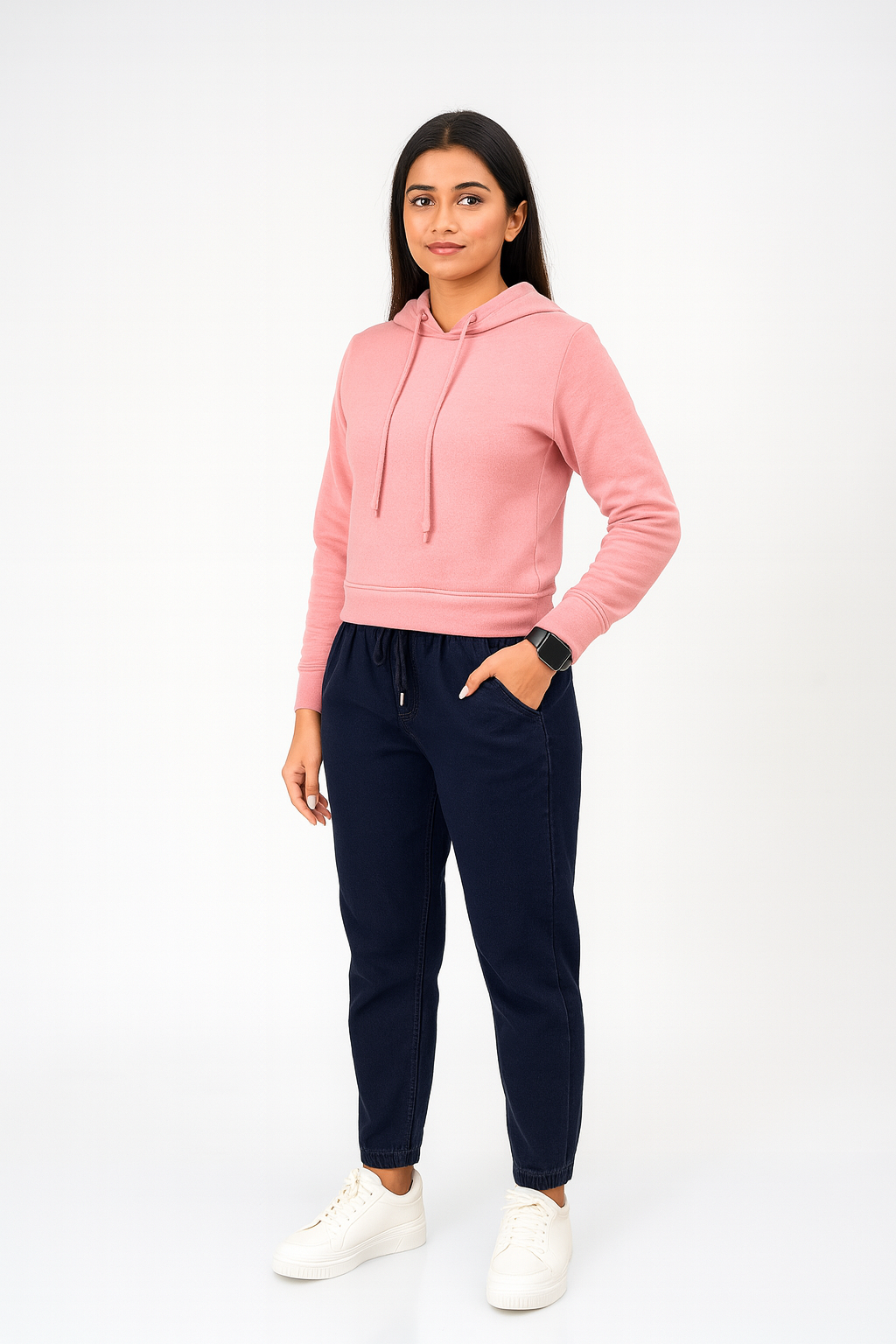 Woman wearing a pink hoodie and navy jogger pants on a white background
