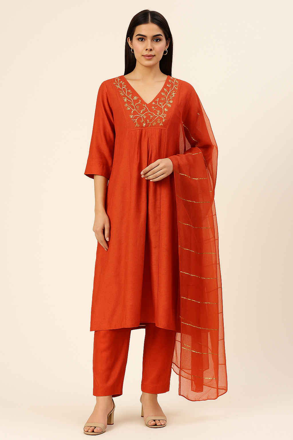 Woman wearing an orange traditional outfit with embroidery on a beige background