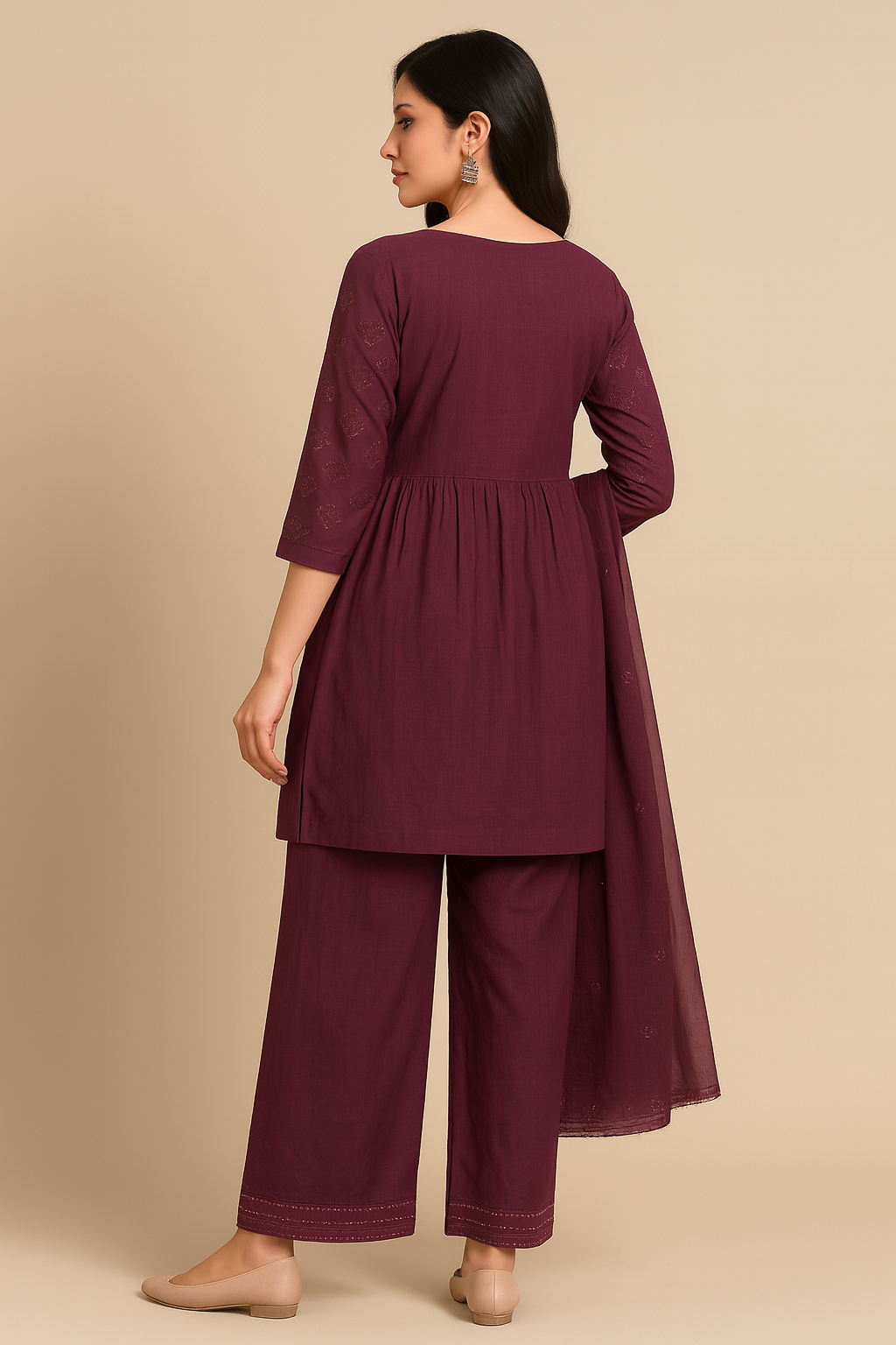 Woman wearing a maroon outfit with a matching top and wide-leg pants on a beige background