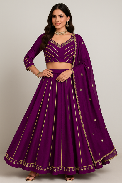 Woman wearing a purple traditional outfit with gold embroidery on a plain background