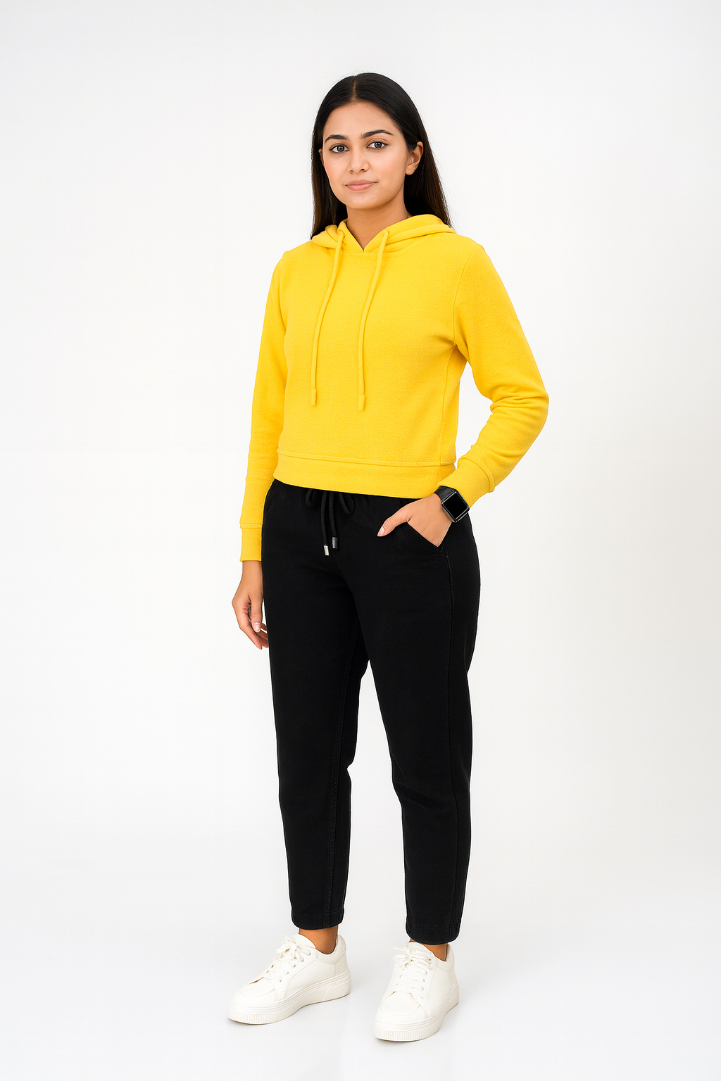 Woman wearing a yellow hoodie and black pants on a white background