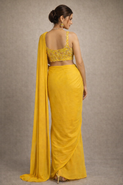 Woman wearing a yellow saree with a plain background
