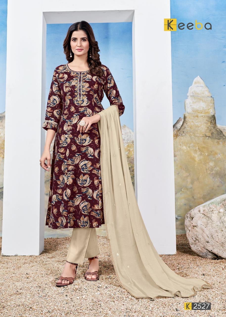 Woman wearing maroon floral kurta set with beige dupatta and trousers, standing outdoors