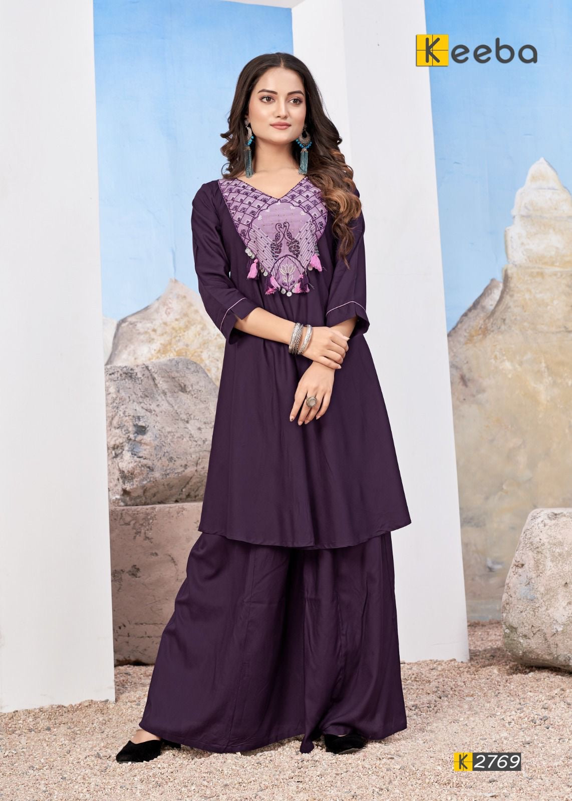 Woman wearing a purple embroidered kurta with palazzo pants, posing indoors